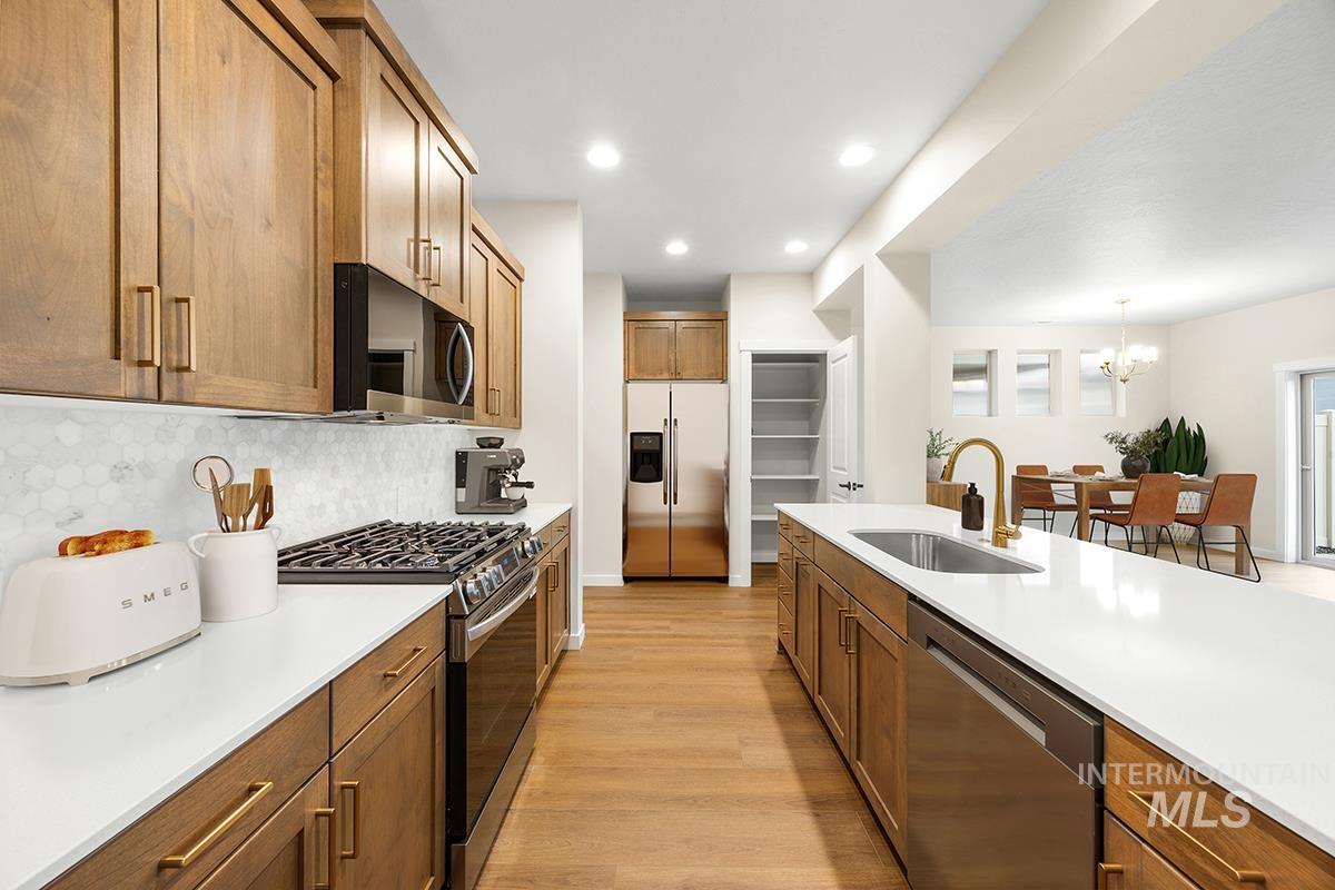 212 West Broyhill Street Meridian, ID 83642 - Photo 3 of 22 Kitchen with stainless steel appliances, light wood finished floors, wood finish cabinetry, backsplash, and hanging lights