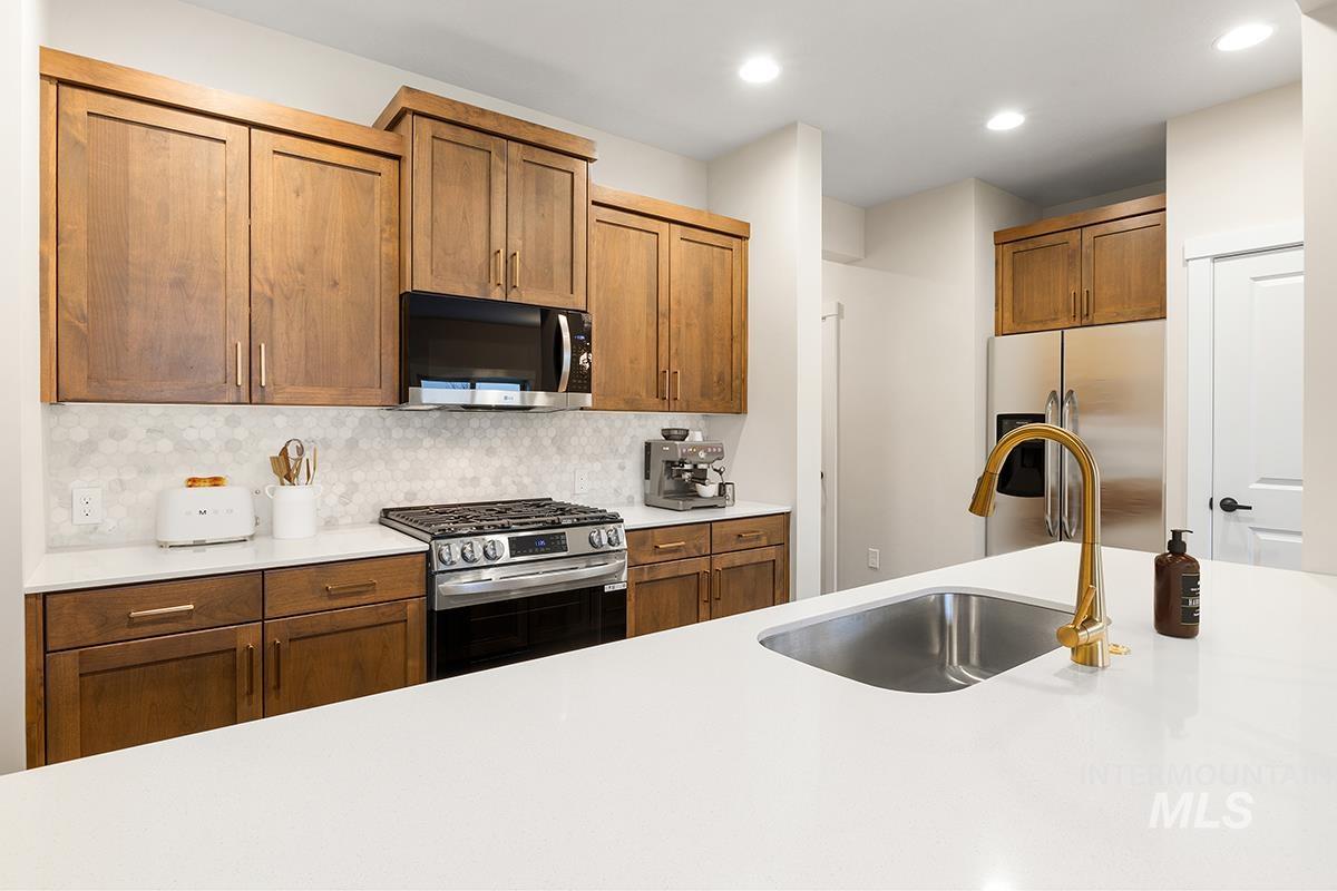 212 West Broyhill Street Meridian, ID 83642 - Photo 4 of 22 Kitchen featuring stainless steel appliances, backsplash, wood finish cabinetry, recessed lighting, and light stone countertops