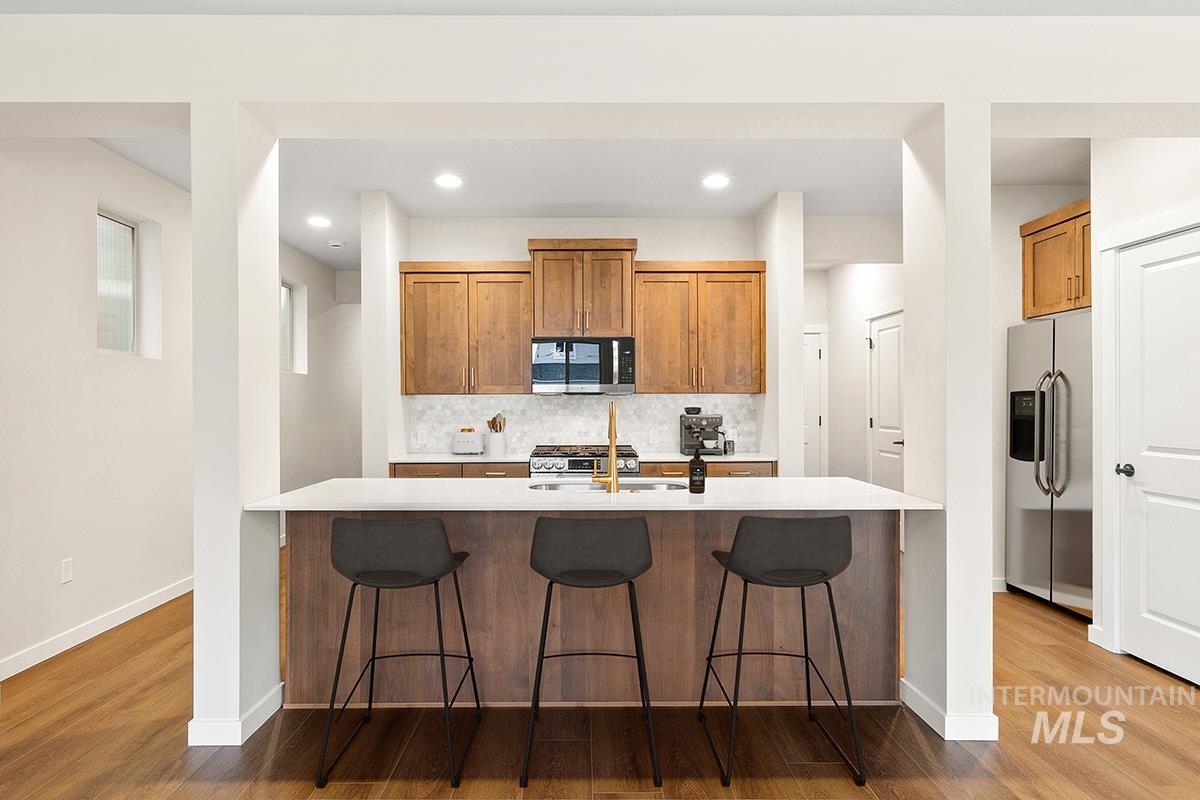 212 West Broyhill Street Meridian, ID 83642 - Photo 5 of 22 Kitchen with wood finish cabinets, stainless steel appliances, a breakfast bar area, dark wood-style flooring, and decorative backsplash