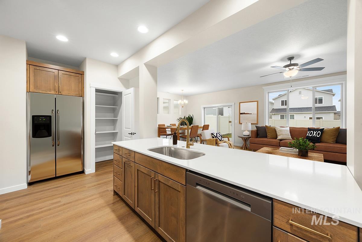 212 West Broyhill Street Meridian, ID 83642 - Photo 22 of 22 Kitchen featuring wood finish cabinetry, stainless steel appliances, ceiling fan, open floor plan, and light wood-type flooring