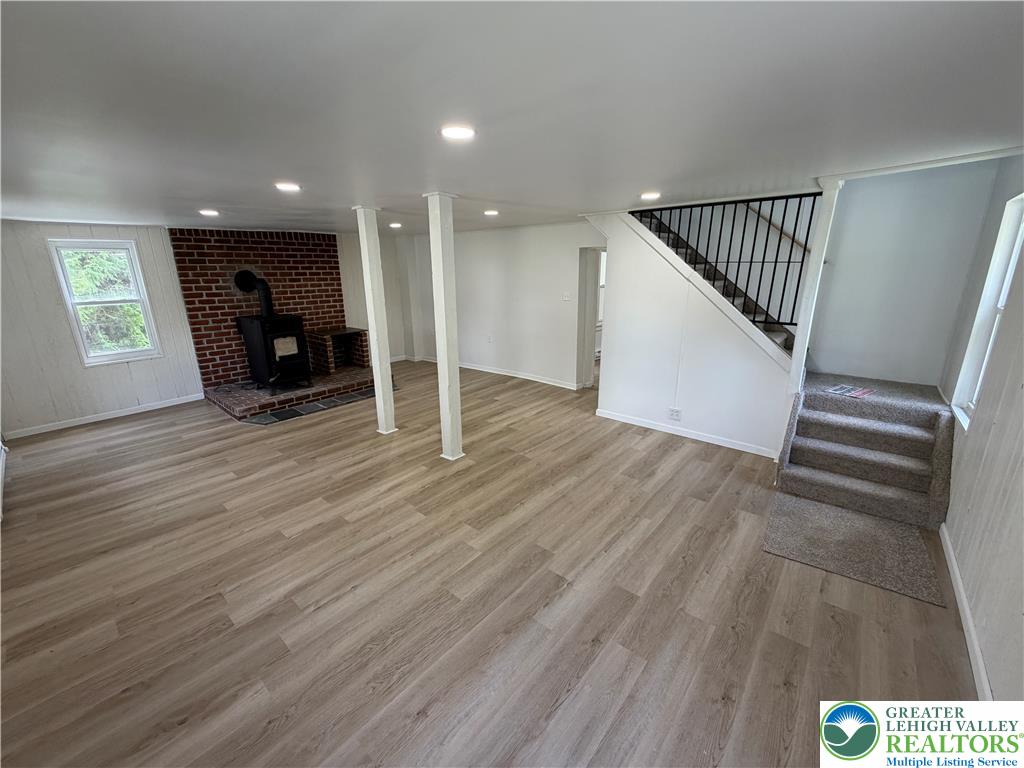 5720 Memorial Road Germansville, PA 18053 - Photo 9 of 29 A welcoming lower-level living space with light wood-style flooring and a cozy brick fireplace feature.