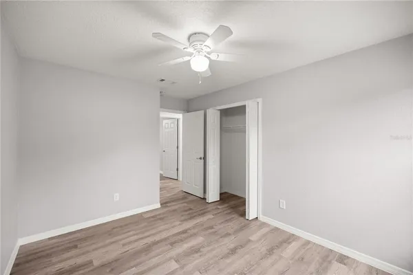 an empty room with wooden floor and ceiling fan