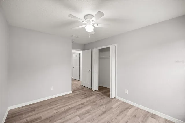 an empty room with wooden floor and ceiling fan