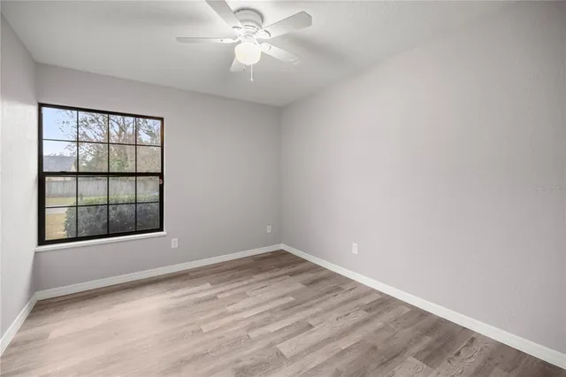 an empty room with a window and ceiling fan