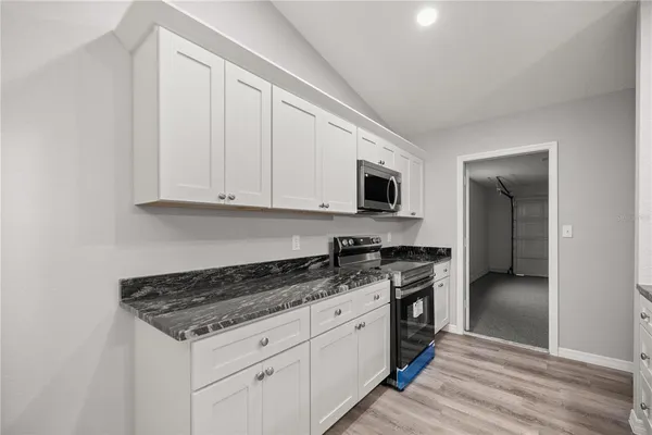 a kitchen with granite countertop a stove top oven a sink dishwasher and cabinets with wooden floor