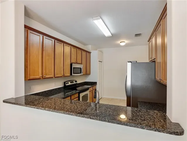 a kitchen with stainless steel appliances granite countertop a refrigerator a stove and a sink with granite countertops