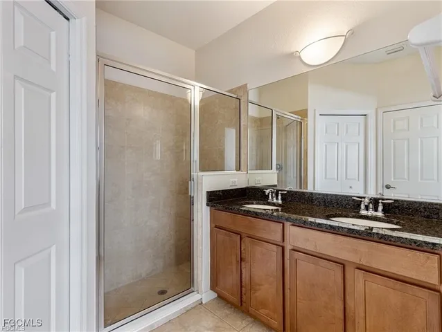 a bathroom with a granite countertop sink a mirror and a shower