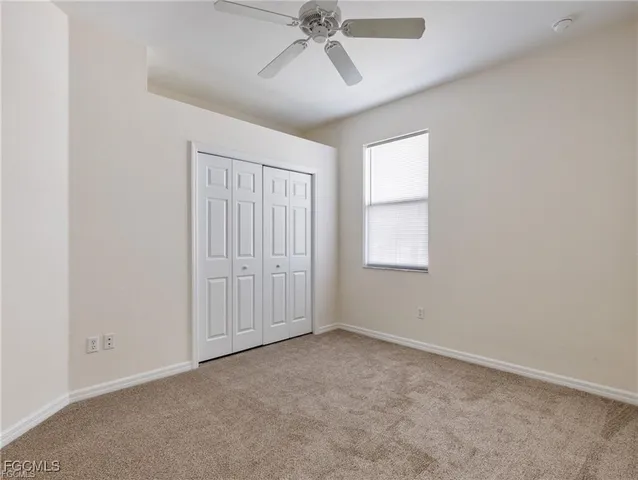 an empty room with chandelier fan and windows
