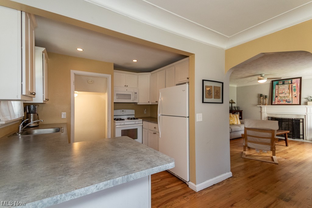 2419 Kingston Road Cleveland, OH 44118 - Photo 11 of 34 Kitchen with light countertops, light hardwood floors, white cabinetry, ceiling fan, a fireplace, and white appliances