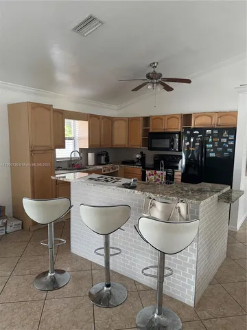a living room with stainless steel appliances granite countertop furniture a fireplace a rug and a window