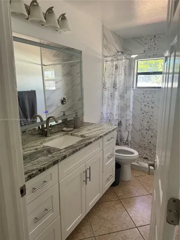 a bathroom with a granite countertop sink a toilet and a mirror