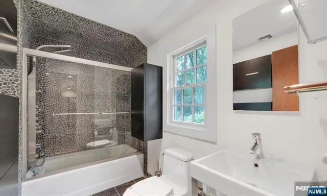 a bathroom with a bathtub shower sink vanity and toilet