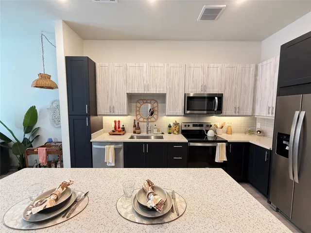 a kitchen with stainless steel appliances kitchen island granite countertop a refrigerator a stove a sink and dishwasher