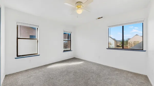 an empty room with windows and fan