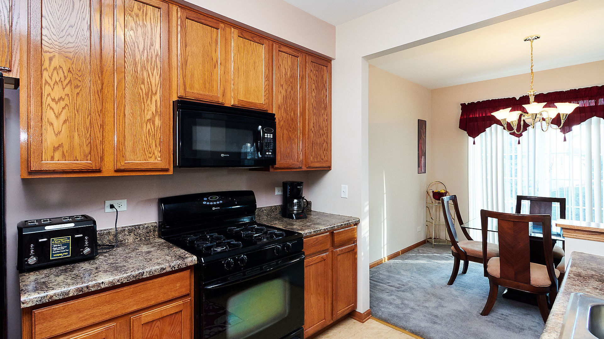 1989 West Cobblestone Road, Unit 1989 Romeoville, IL 60446 - Photo 17 of 51 a kitchen with stainless steel appliances granite countertop a stove a sink a microwave and dining table