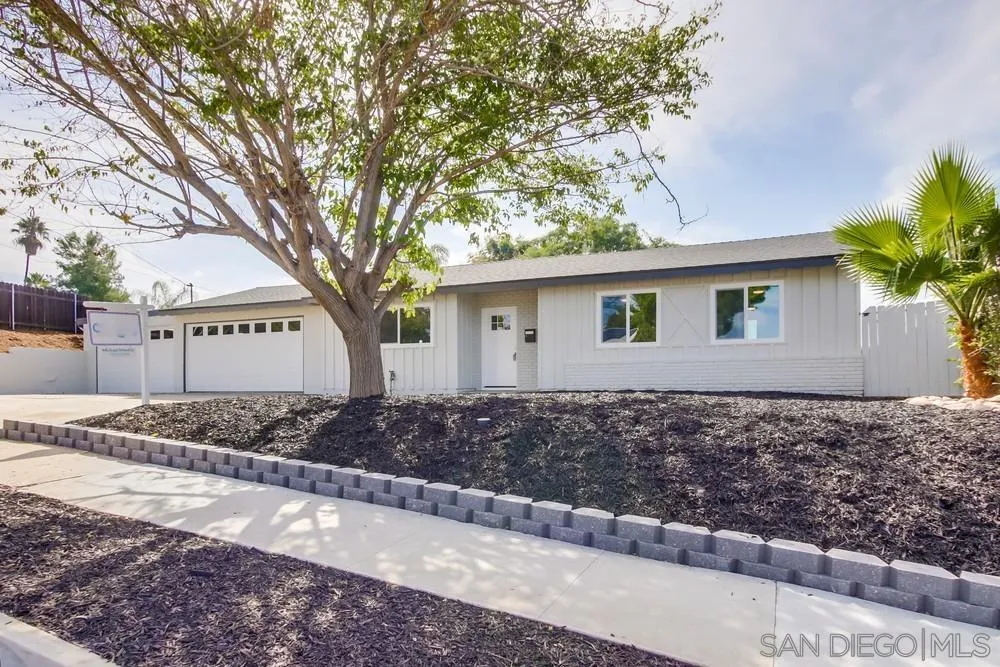 a view of a house with a yard and large tree