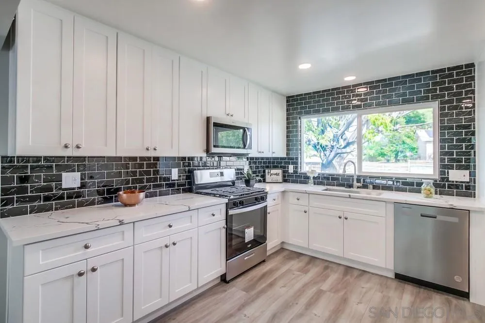 10110 Strathmore Drive Santee, CA 92071 - Photo 8 of 45 a kitchen with granite countertop white cabinets white appliances a sink and a window