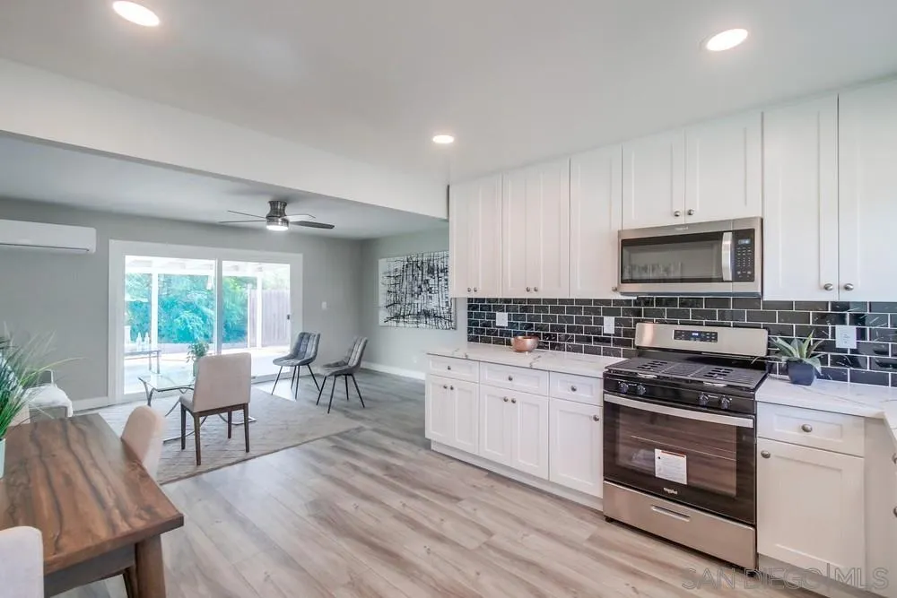 10110 Strathmore Drive Santee, CA 92071 - Photo 9 of 45 a kitchen with stainless steel appliances granite countertop a stove top oven a sink dishwasher a dining table and chairs with wooden floor
