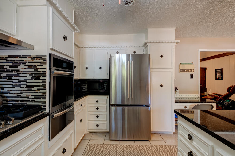 4509 62nd Street Lubbock, TX 79414 - Photo 9 of 20 a kitchen with granite countertop a refrigerator and a stove top oven