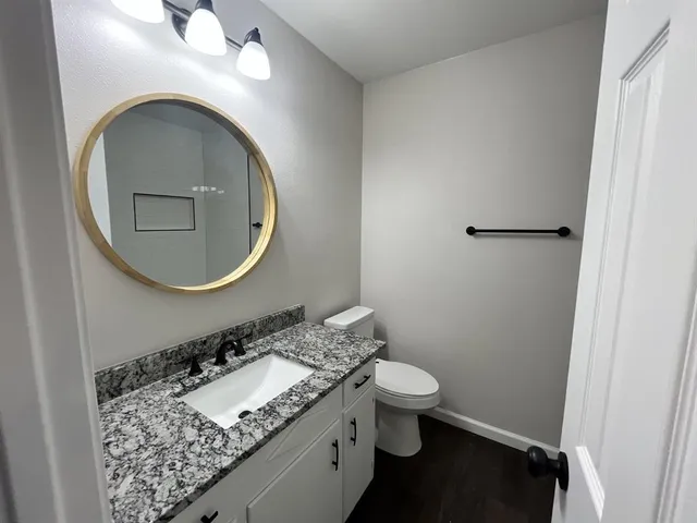 a bathroom with a granite countertop toilet and a sink