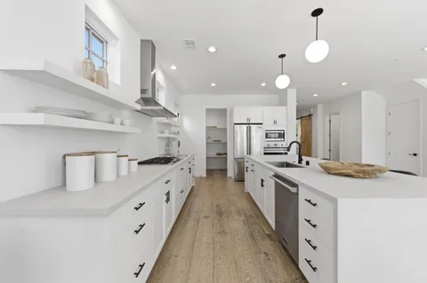a large kitchen with stainless steel appliances lots of counter space and windows