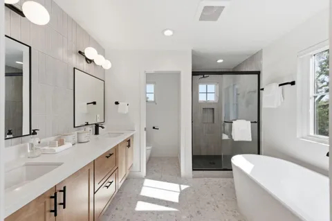 a spacious bathroom with a double vanity sink a large mirror and a bathtub