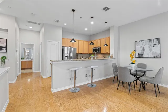 a large white kitchen with a refrigerator a dining table and chairs