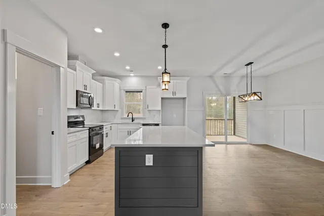 a large kitchen with kitchen island a stove a sink a center island and cabinets