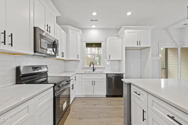 a kitchen with stainless steel appliances granite countertop a sink a stove a refrigerator and island with wooden floor