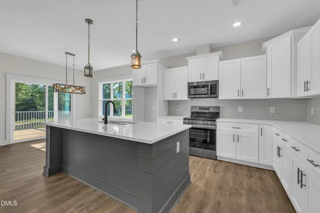 a kitchen with kitchen island a sink stainless steel appliances and white cabinets