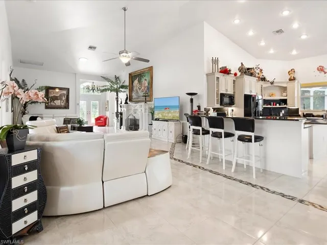 a room with lots of white furniture and a chandelier