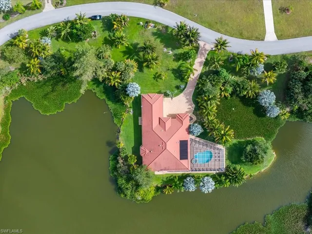 an aerial view of a house with a yard lake and outdoor seating