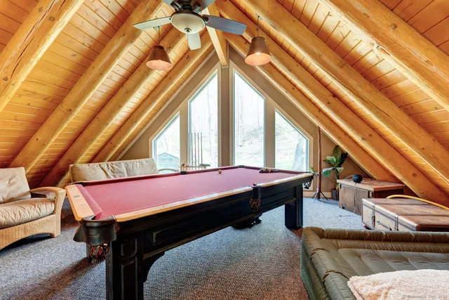a room with wooden floor pool table and chairs
