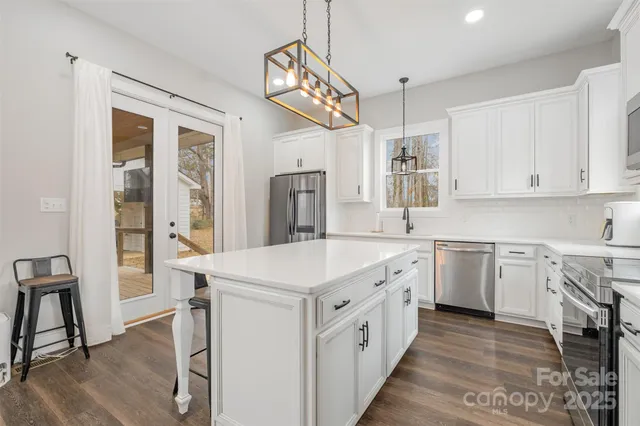 a kitchen that has a lot of white cabinets and wooden floor