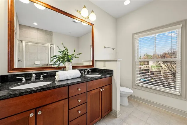 a bathroom with a granite countertop sink a large mirror a toilet and a shower