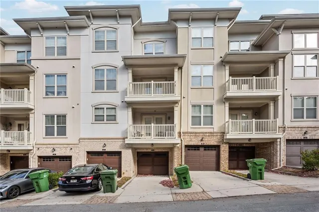 a front view of a residential apartment building with a yard and parking space