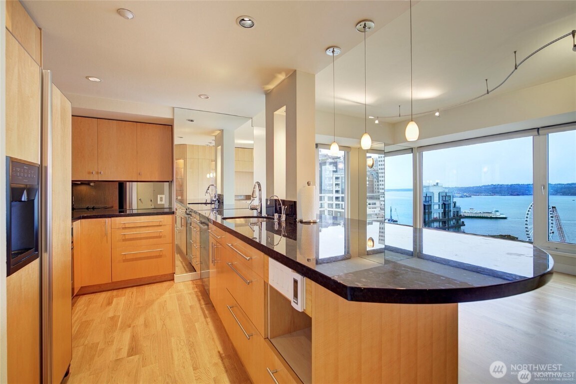 1415 2nd Avenue, Unit 1209 Seattle, WA 98101 - Photo 9 of 21 a view of a kitchen with kitchen island a large window a sink and cabinets