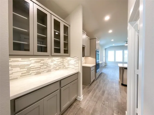 a view of a kitchen with kitchen island a sink wooden floor and a large window
