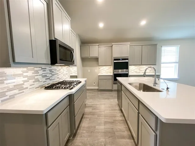 a kitchen with a sink stove top oven and refrigerator