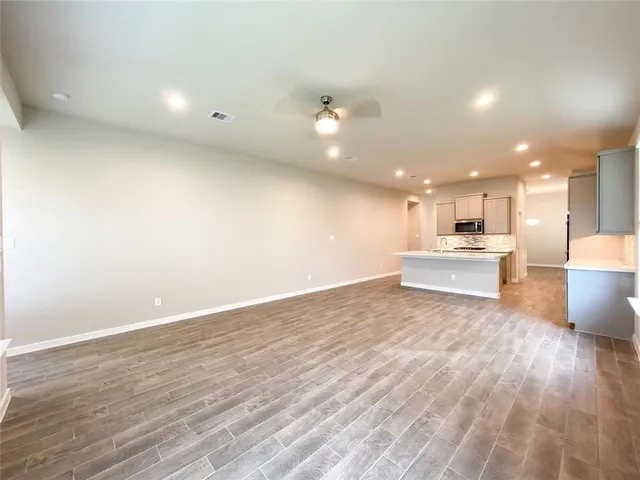 a view of kitchen with kitchen island wooden floor center island and stainless steel appliances
