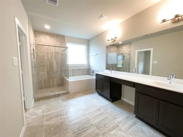 a bathroom with a double vanity sink a large mirror and bathtub