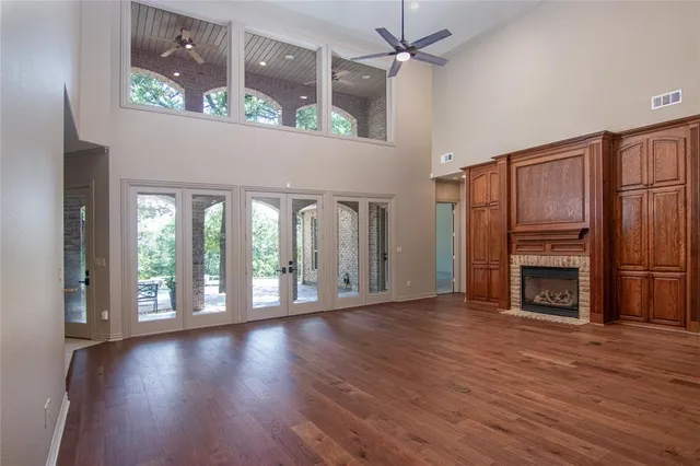 an empty room with wooden floor fireplace and windows