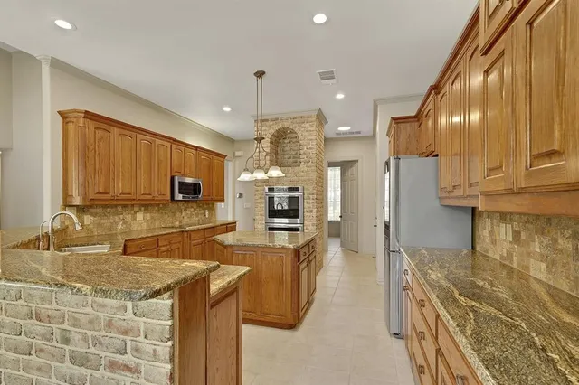 a kitchen with stainless steel appliances granite countertop a sink a stove and a refrigerator