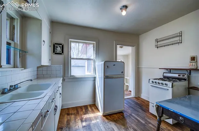 a kitchen with a refrigerator a sink and wooden floor