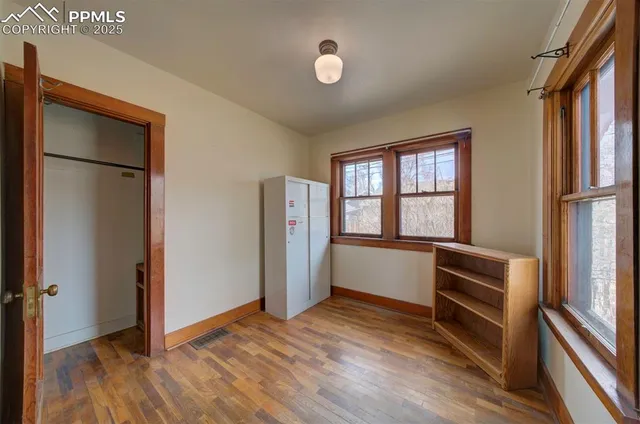 a view of an empty room with a window and wooden floor