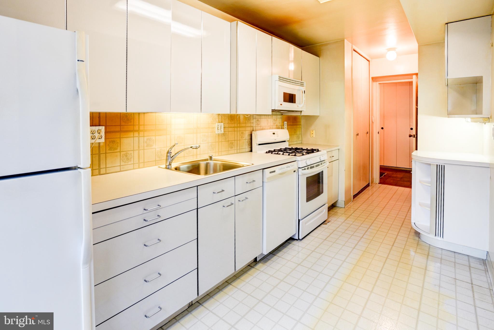 4201 Cathedral Avenue Northwest, Unit 201E Washington, DC 20016 - Photo 13 of 66 a kitchen with granite countertop white cabinets and white appliances