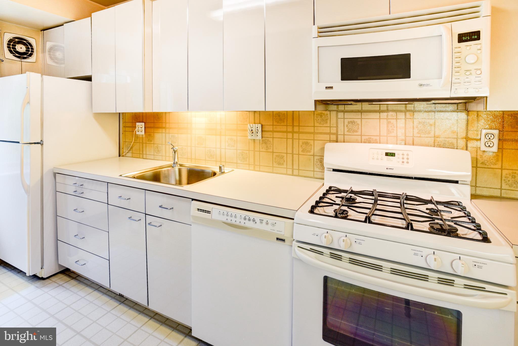 4201 Cathedral Avenue Northwest, Unit 201E Washington, DC 20016 - Photo 18 of 66 a kitchen with white cabinets and white appliances