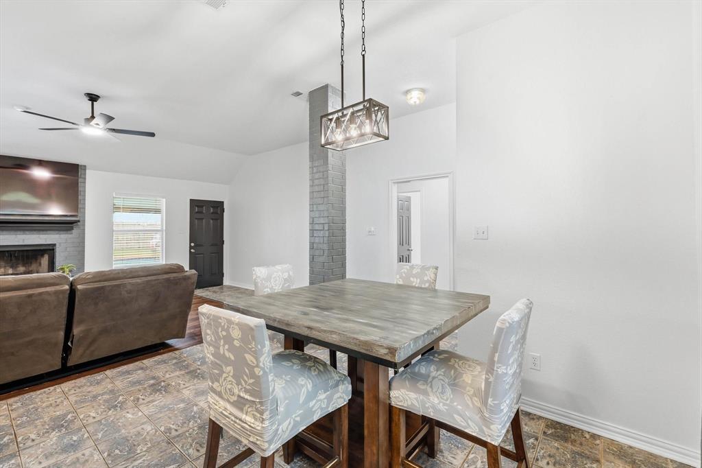 217 Seay Road Italy, TX 76651 - Photo 11 of 38 Dining area with vaulted ceiling, a brick fireplace, ceiling fan, and beautiful finish floors