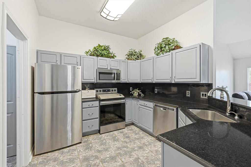 217 Seay Road Italy, TX 76651 - Photo 13 of 38 Kitchen with stainless steel appliances, backsplash, dark stone countertops, and gray cabinetry