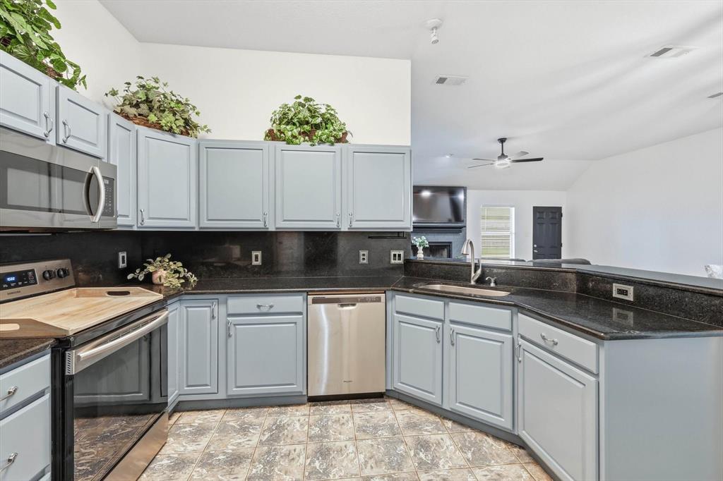 217 Seay Road Italy, TX 76651 - Photo 14 of 38 Kitchen with stainless steel appliances, gray cabinets, dark stone counters, vaulted ceiling, and backsplash